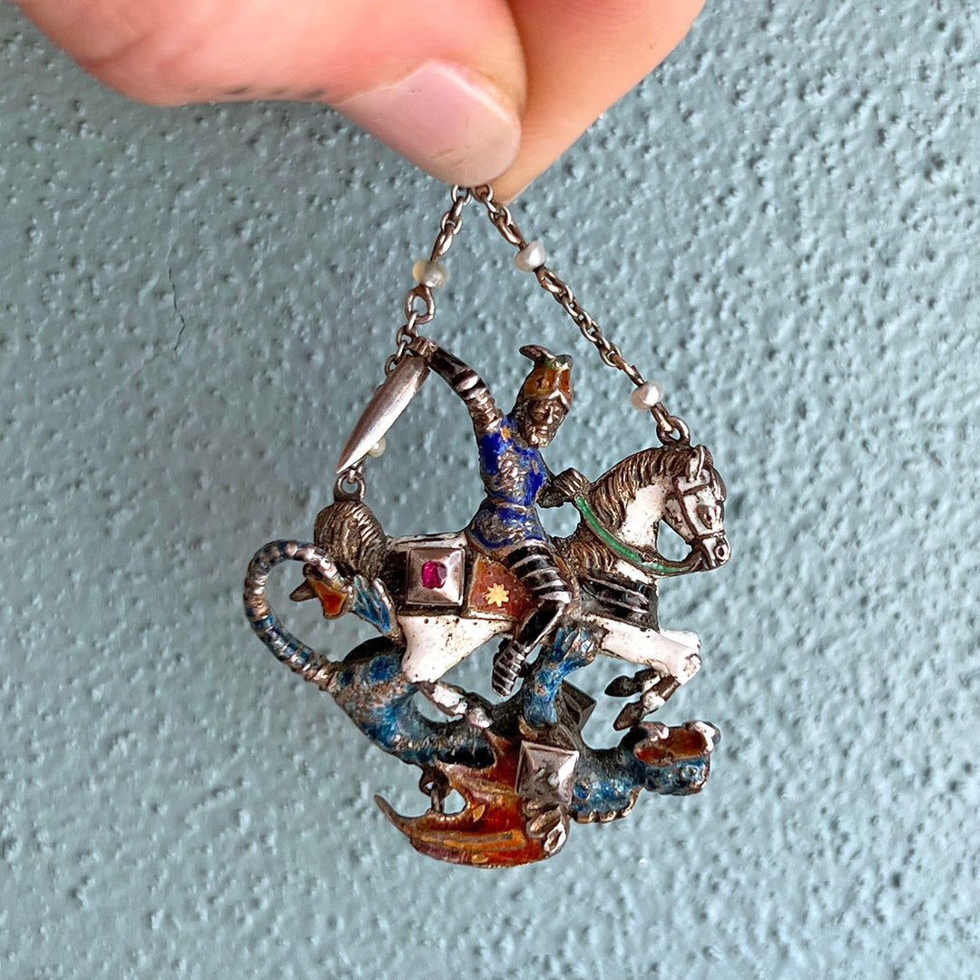 Close up antique enamel pendant showing detailed figural scene