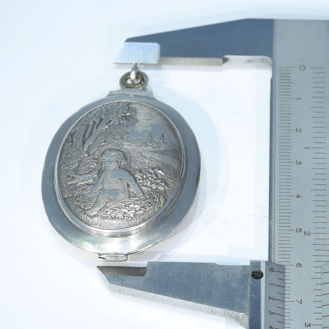 Antique silver slide locket featuring a baby in a nest