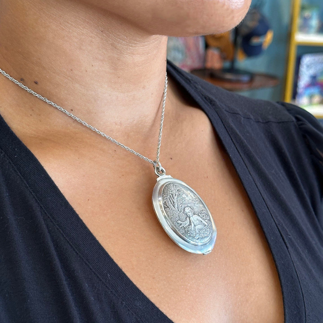 Antique silver slide locket featuring a baby in a nest