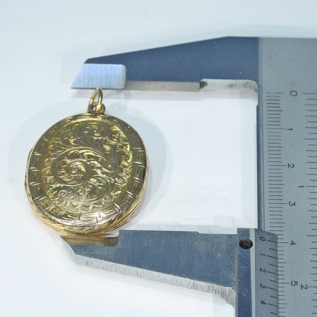 Antique oval gold locket decorated with leaves and scrolls
