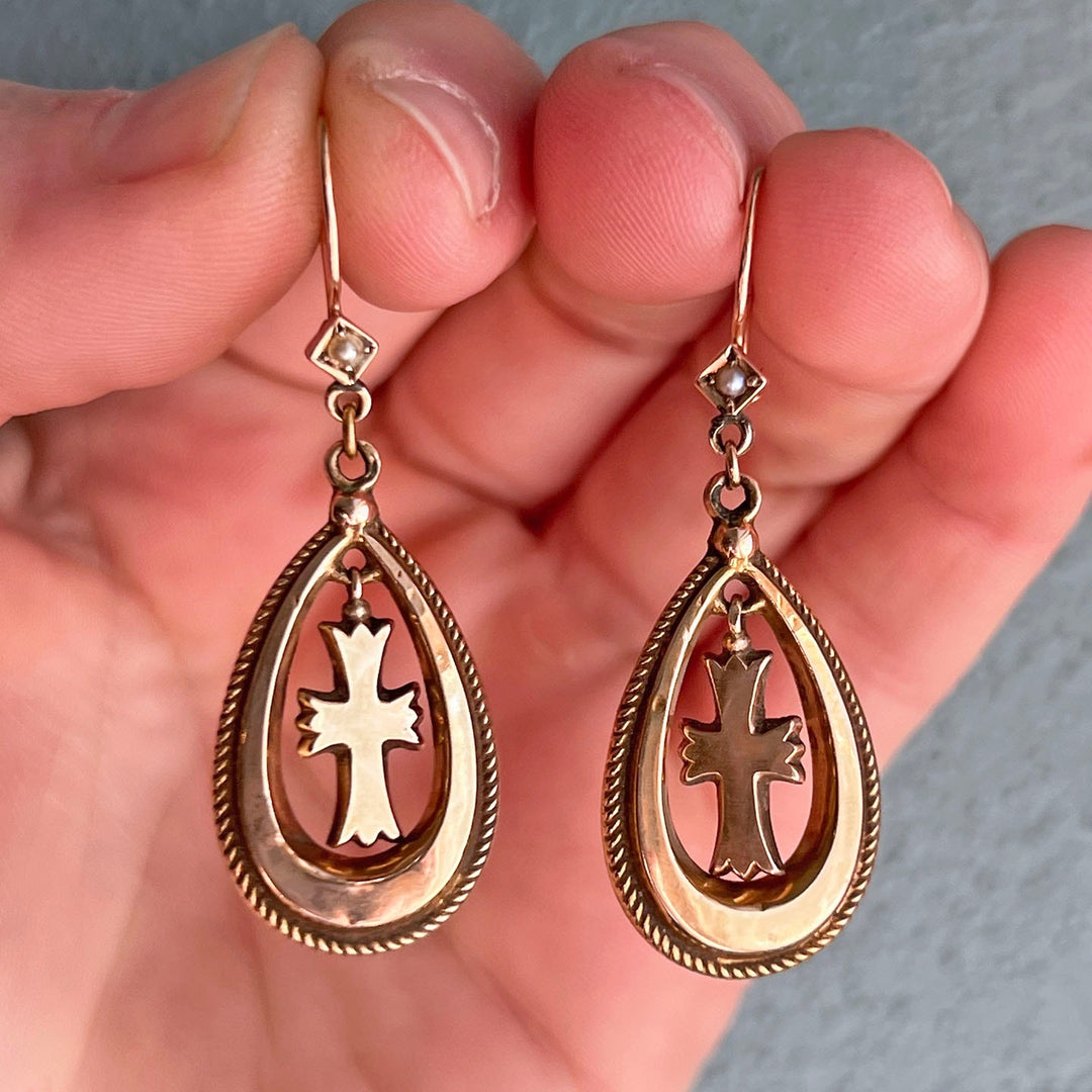 Close view of gold cross earrings with pearls